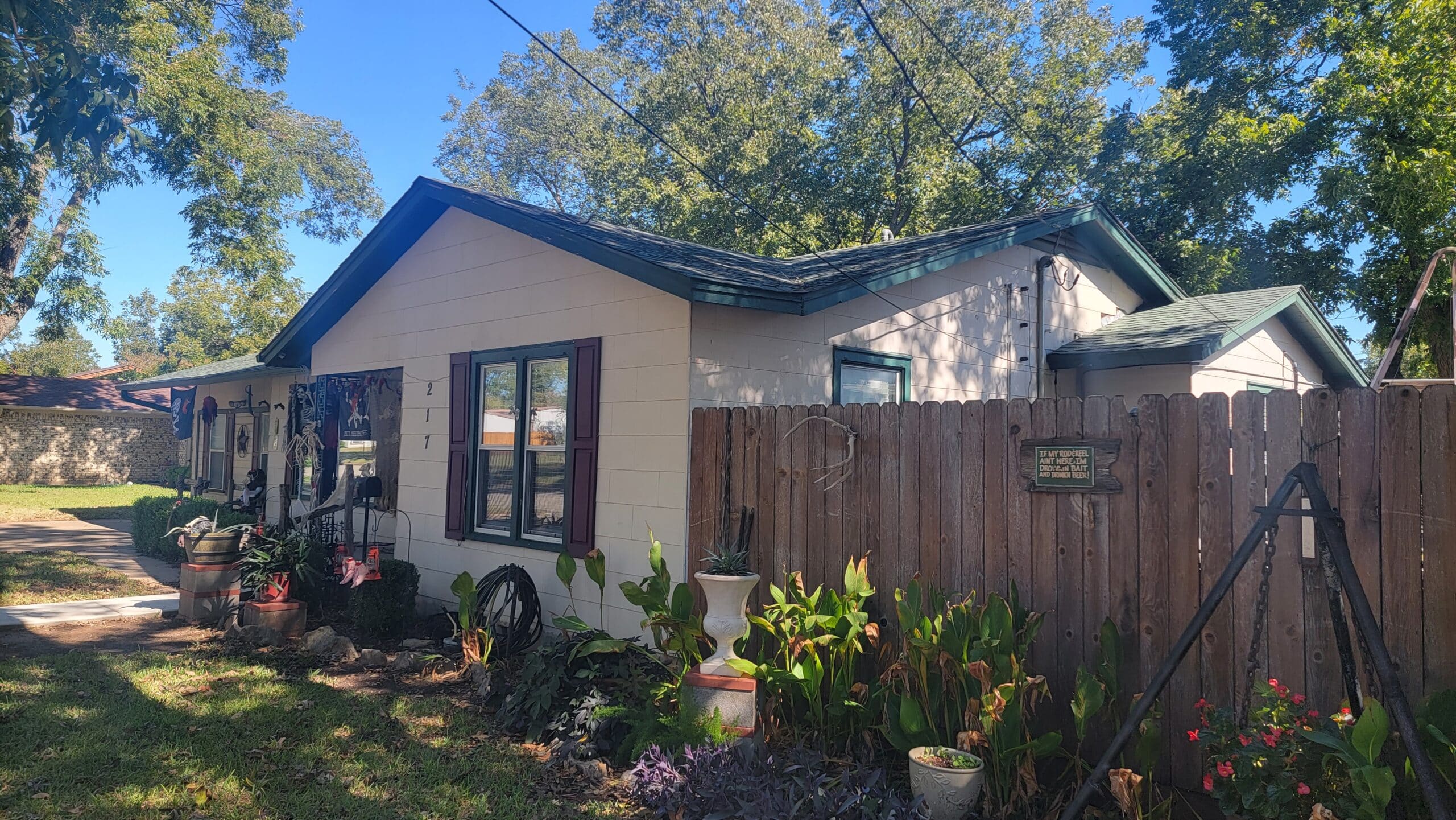 Front view of a home in Burleson Texas with a cedar fence and landscaping, that is need of some new siding and window replacement