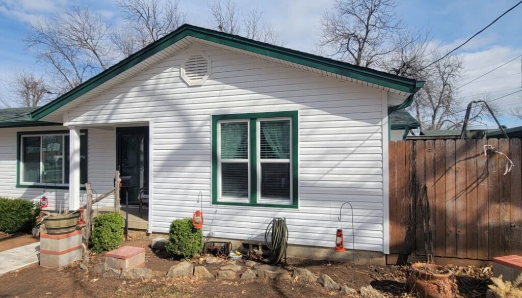 Exterior view of a white country house that has Dutch lap siding with Grecian green accents