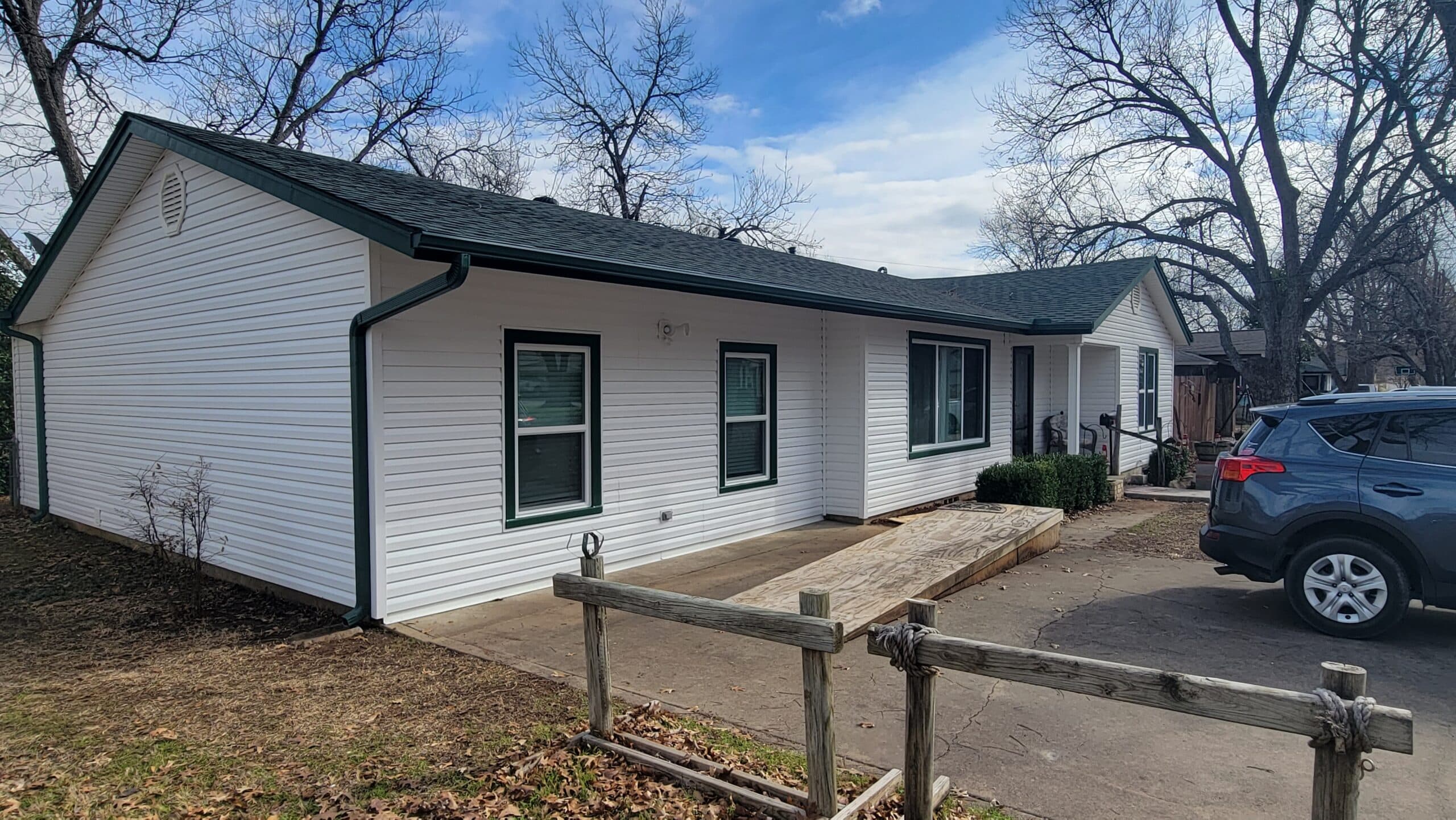 Front view of a country home in Burleson after getting new white CraneBoard vinyl siding with Grecian Green accents.