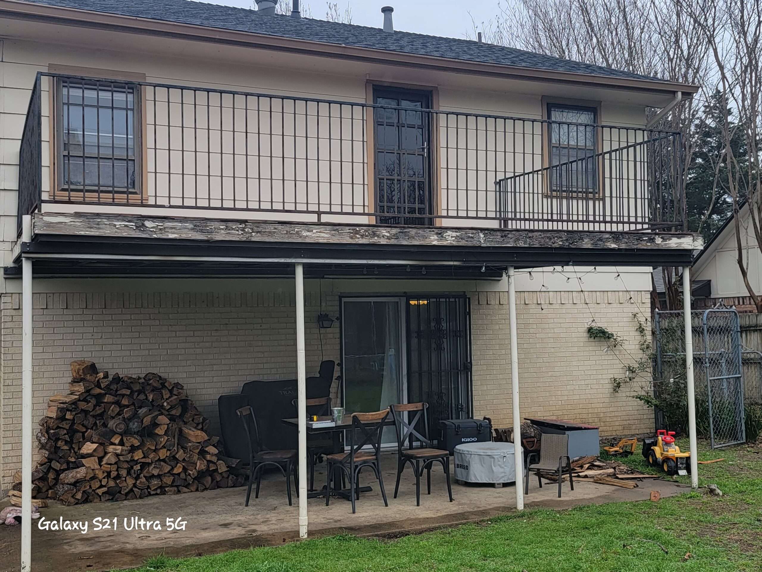 A home with old siding and windows and an unsafe deck on the second floor.