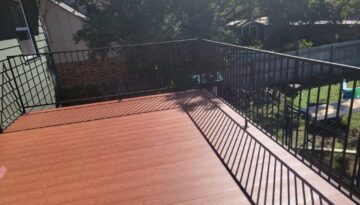 Standing on a second story deck looking at Nexan Lock Dry Aluminum Decking in a woodgrain light oak powder coated finish and black hand railing.