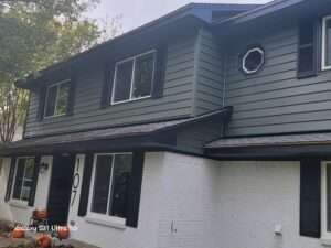 CraneBoard laminated vinyl siding in spruce color with black accents and white vinyl windows.