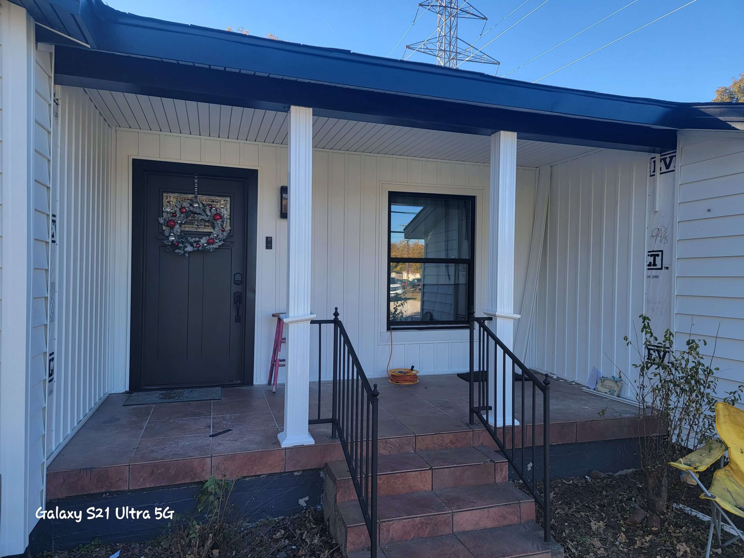 Front view of a home in Hurst Texas that has new Prodigy vinyl siding, Vistamark vinyl windows, AFSCO aluminum Columns and a Fiberglass Entry Door. The siding and columns are white, with black accents, black windows and entry door.