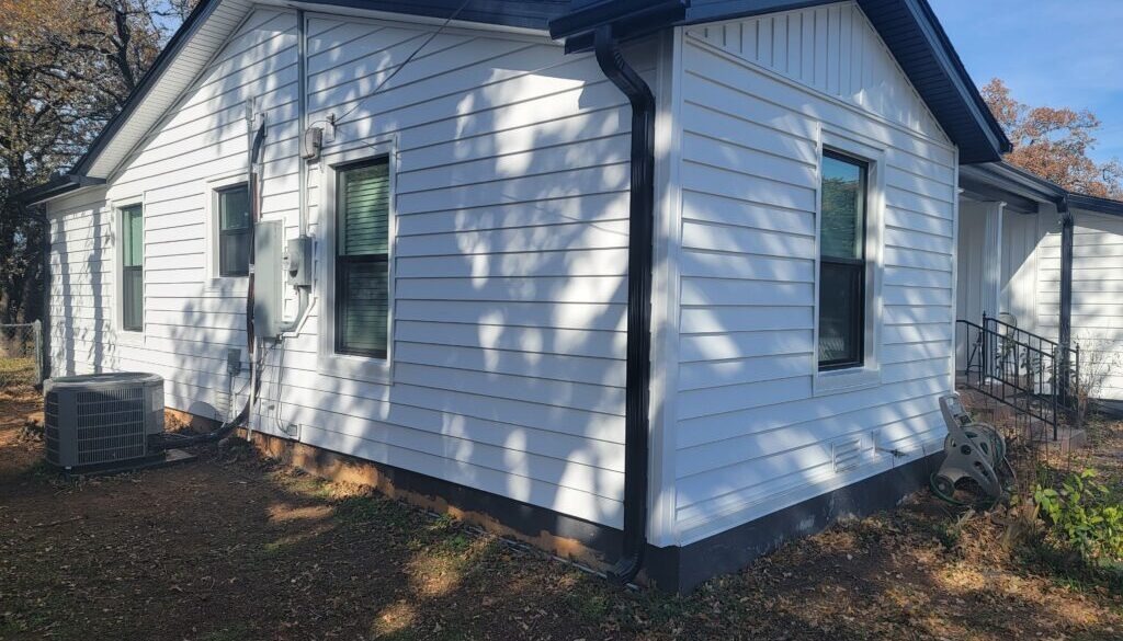 Front view of a white cottage style home with Board and batten gables, Prodigy Laminated Lap Siding, Black Vistamark windows and matching black trim accents