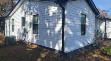 Prodigy insulated siding in dutch lap white with board and batten gables, black gutters and new vinyl windows