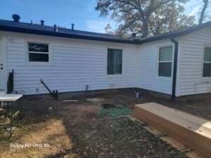 Rear view of a white house in Hurst Texas that has new Prodigy vinyl siding with black accents and new Vistamark Vinyl windows installed.