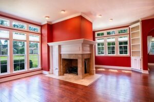 A red living room with oak hardwood floors and a central foreplace with large windows surrounding it